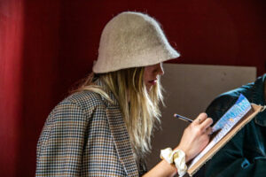 A girl wearing a hat is writing