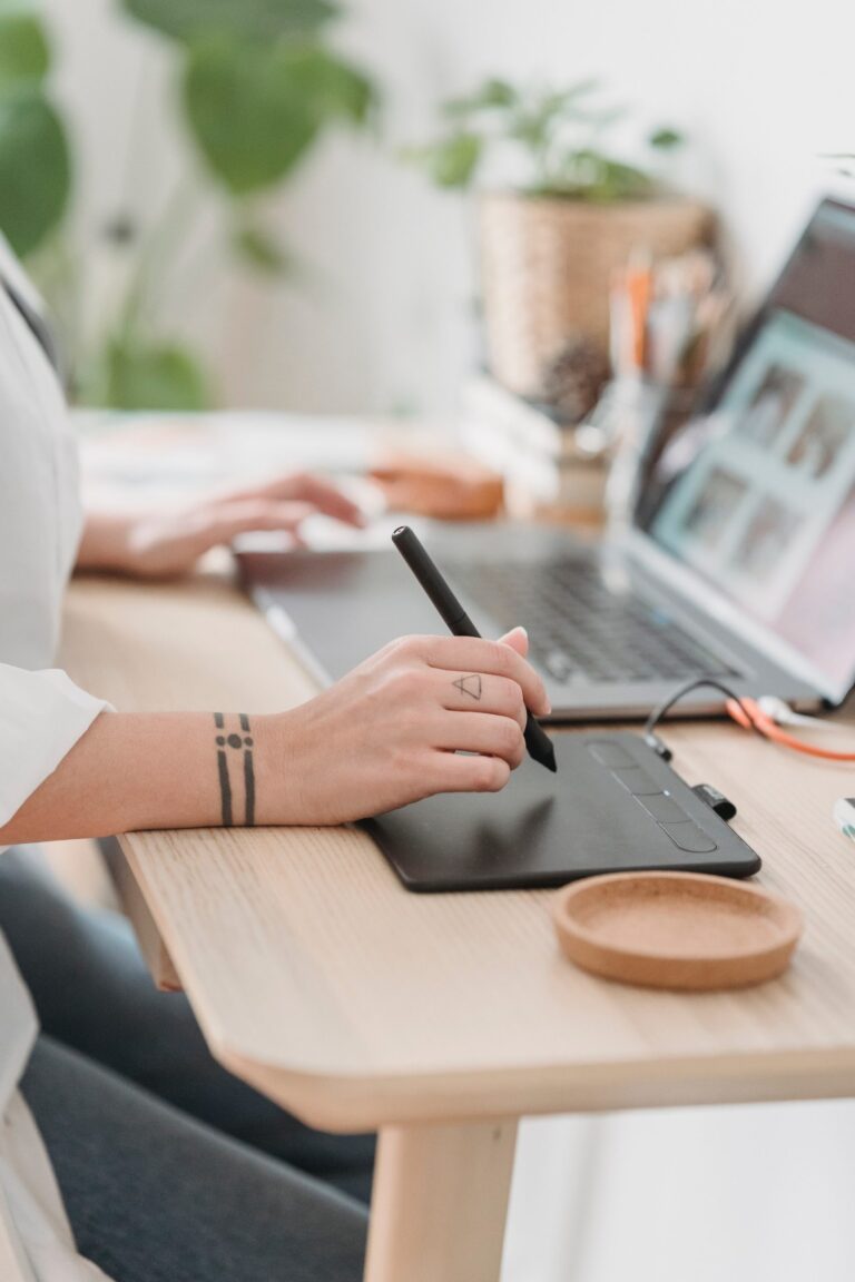 Illustrator drawing on a tablet, on a table, in front of a screen