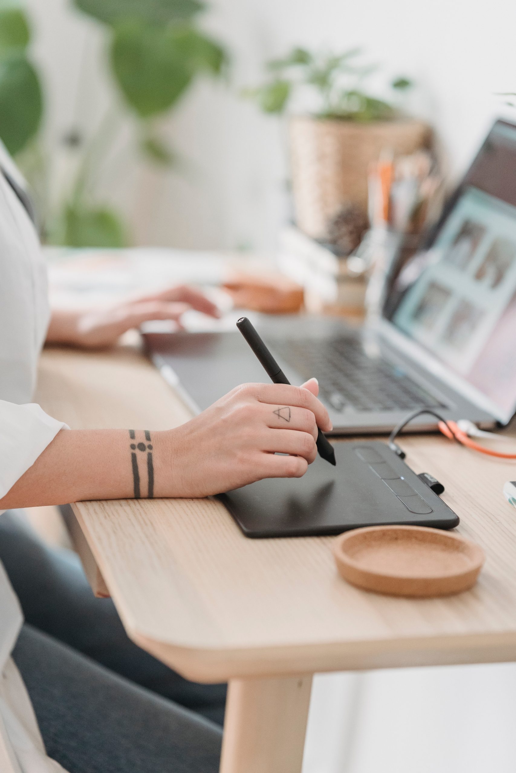 Illustrator drawing on a tablet, on a table, in front of a screen