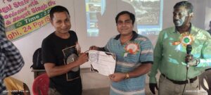 Two people holding a paper of the prize and smiling