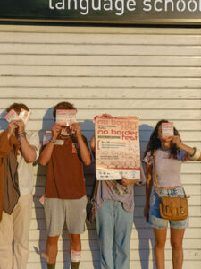 4 people covering their faces with No Borders fest posters