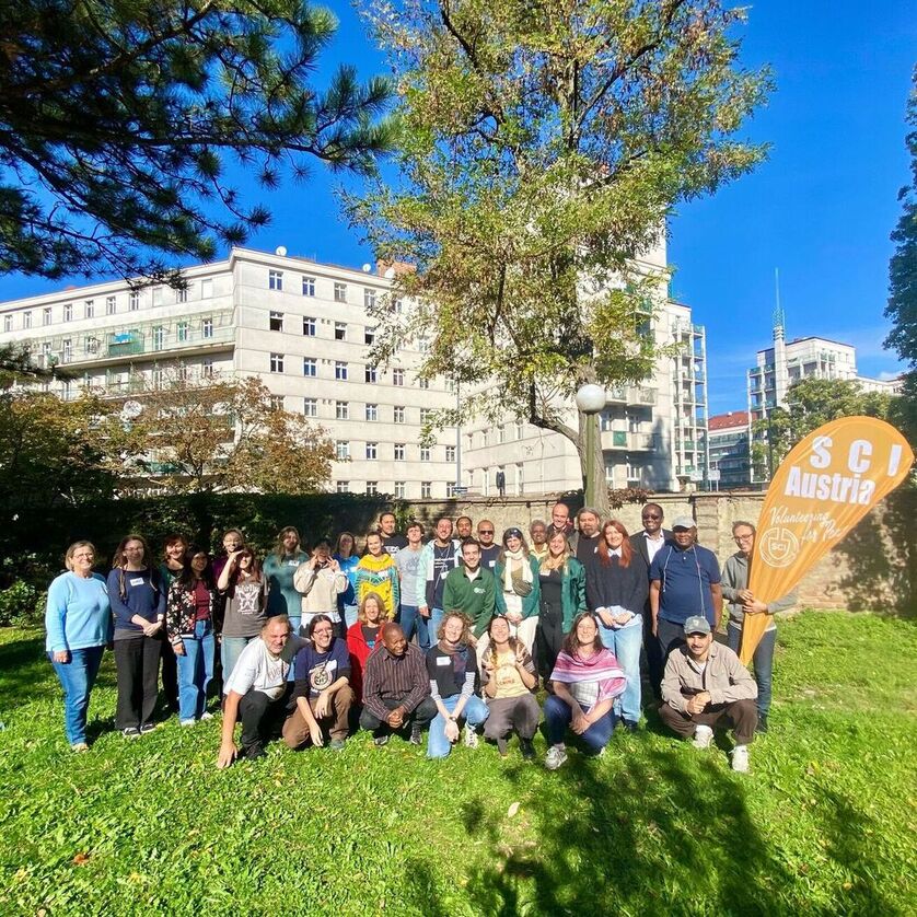 EPM 2024, group of people posing for a photography, they have a flag that says SCI Austria, Volunteering for Peace